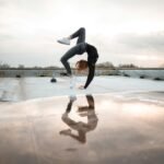 woman doing bridge posts reflecting on water puddle